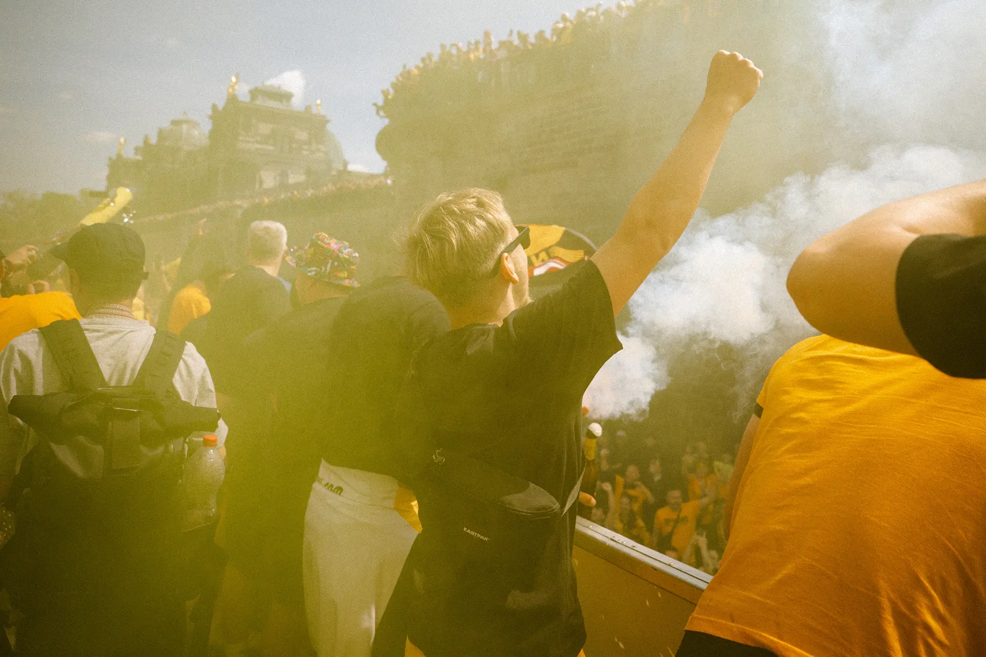 Menschen in gelben und schwarzen Kleidern feiern bei einem sonnigen Outdoor-Event.