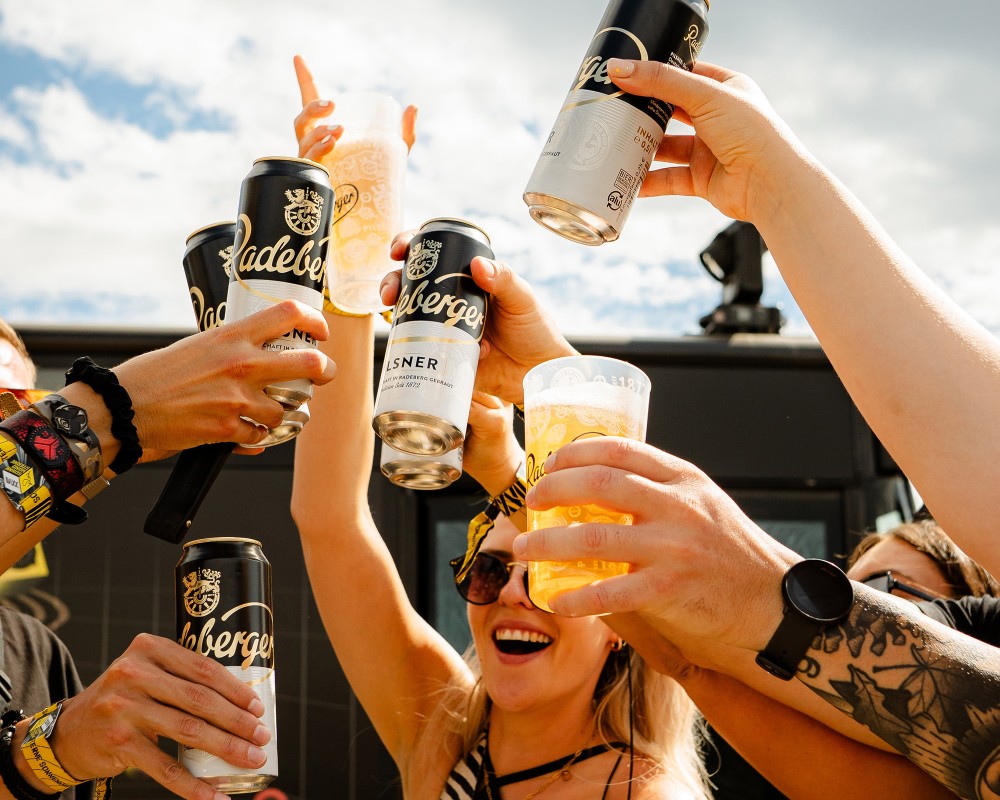 Menschen stoßen mit Radeberger-Bier an, fröhliche Stimmung im Freien.
