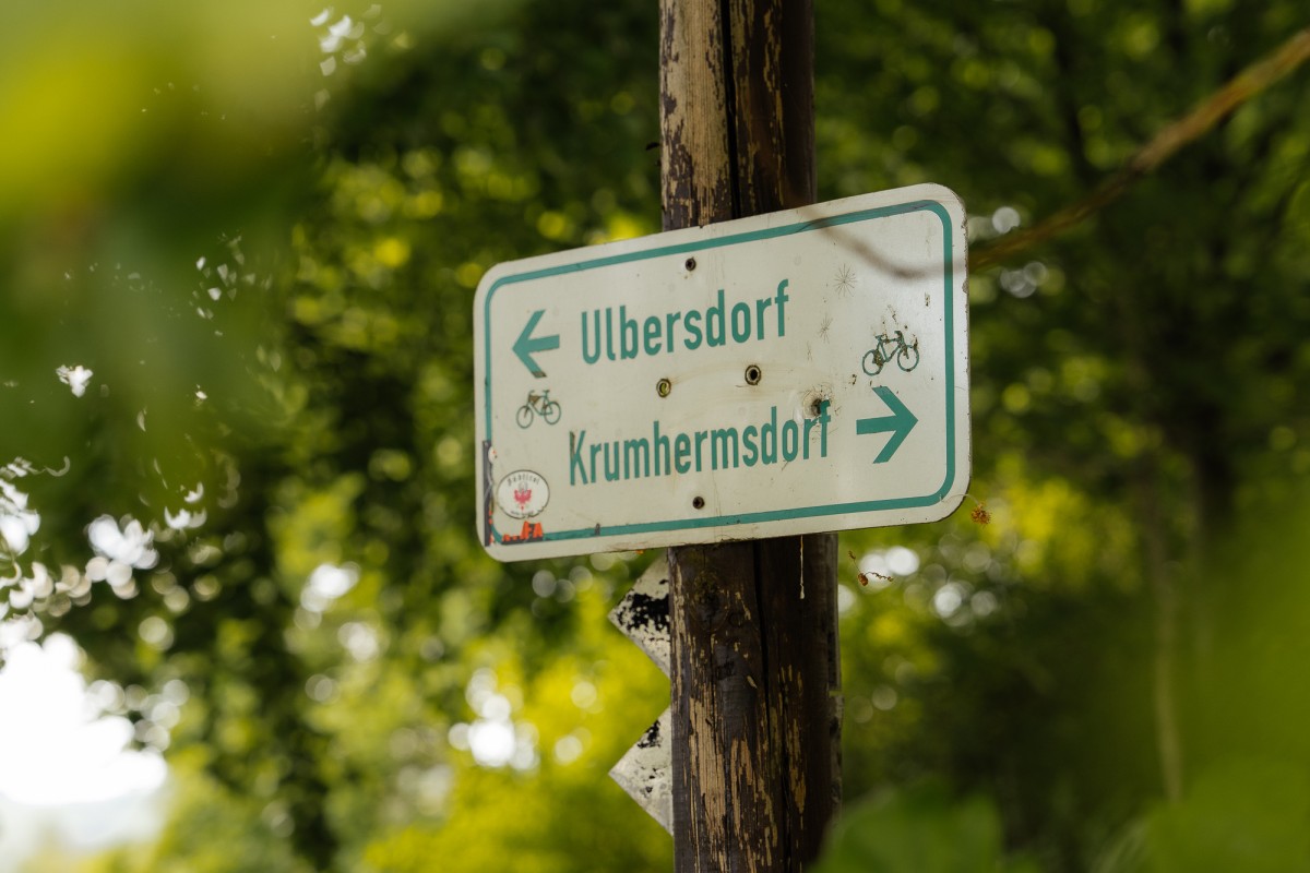 Ein Schild am Baum weist links nach Ulbersdorf und rechts nach Krumhermsdorf